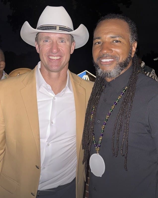 Usama Young smiling at an evening event, wearing beads and a medallion