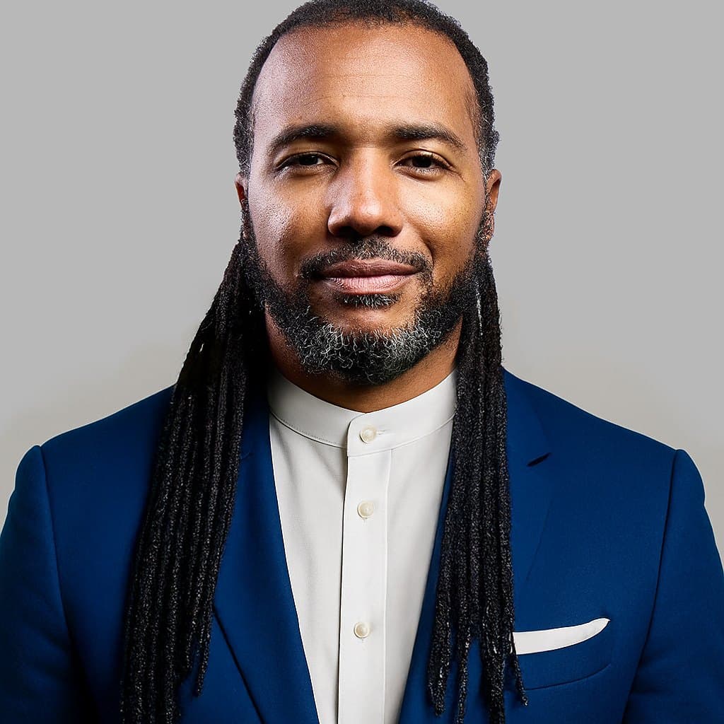 Usama Young in a navy suit, looking at the camera