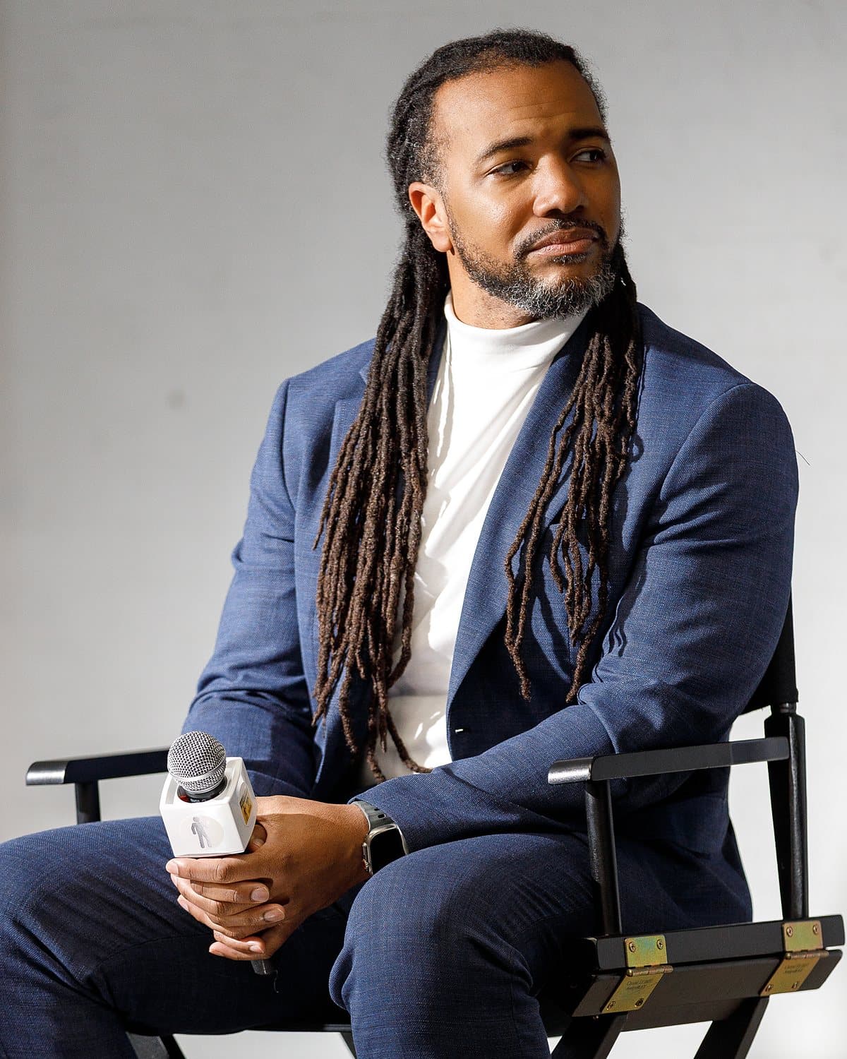 Usama Young seated in a director's chair holding a microphone