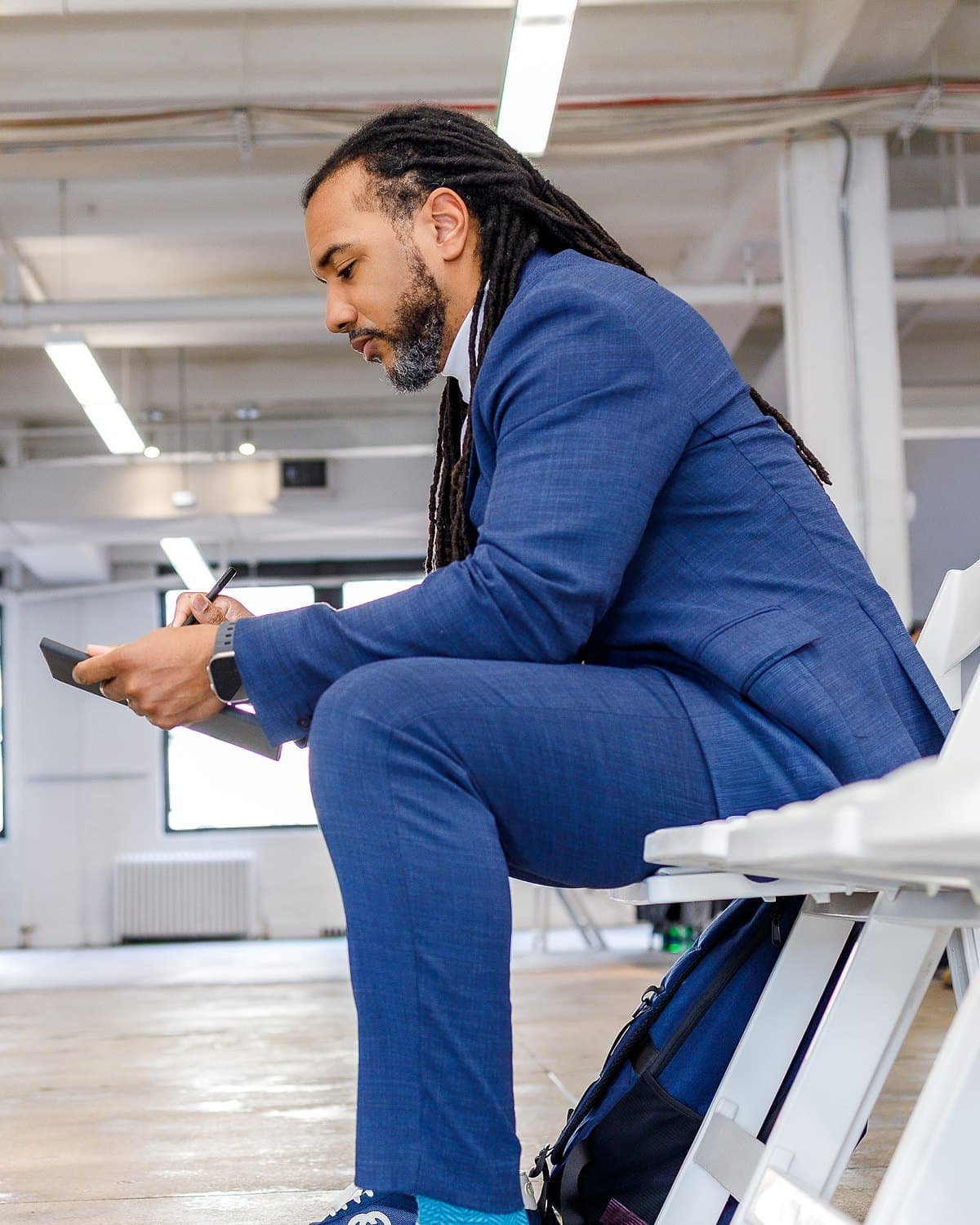 Usama Young in a navy suit, writing in a notebook, side profile